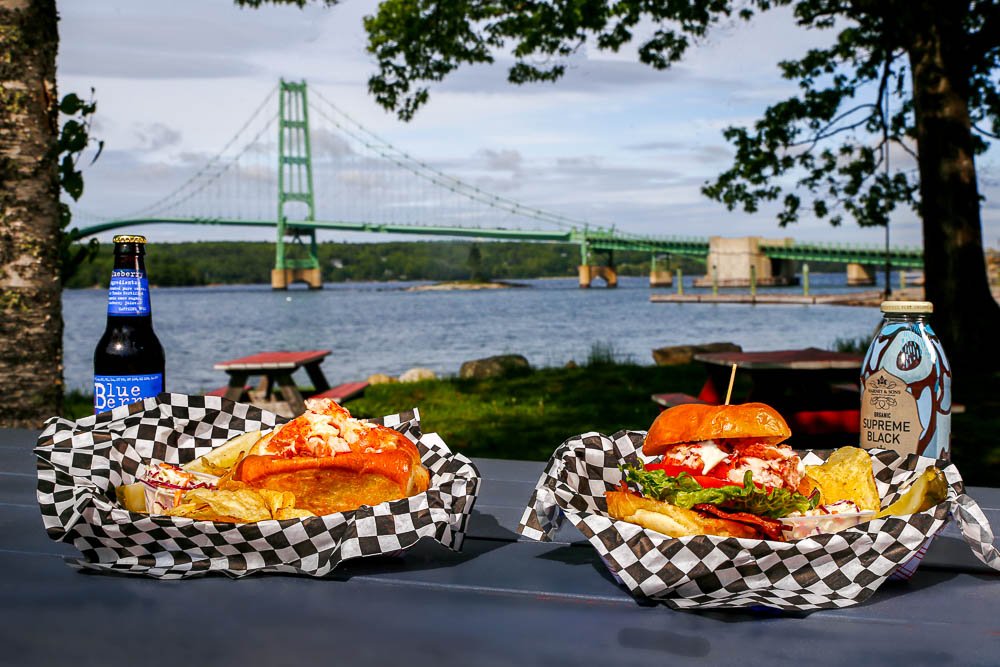 Baskets of food on picnic table overlooking Deer Isle bridge